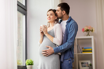 Image showing man hugging pregnant woman at window at home