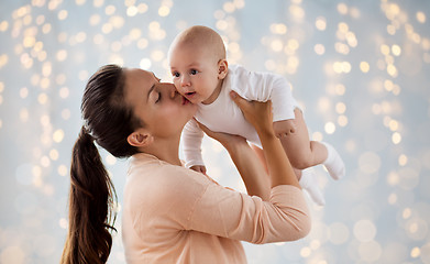 Image showing happy mother kissing little baby boy over lights