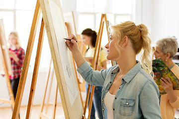 Image showing woman with easel drawing at art school studio