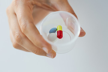 Image showing close up of female hand with pills in medicine cup