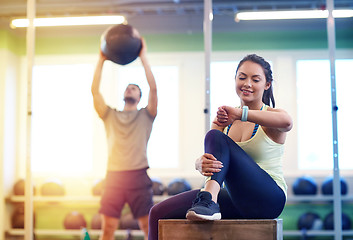 Image showing man and woman with ball and fitness tracker in gym