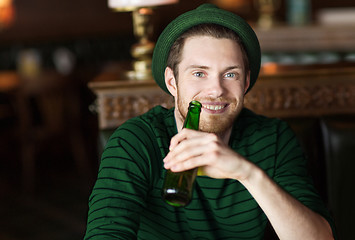 Image showing man drinking beer from green bottle at bar or pub