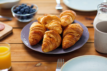 Image showing plate of croissants on wooden table at breakfast