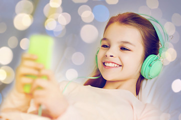 Image showing girl in headphones with smartphone over lights