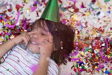 Image showing kid blowing confetti while lying on the floor