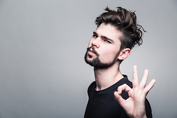 Image showing Young man in  black T-shirt shows gesture ok