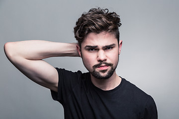 Image showing Young handsome man doubting on gray background 