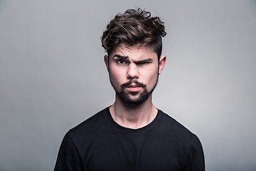 Image showing Young handsome man doubting isolated over gray 