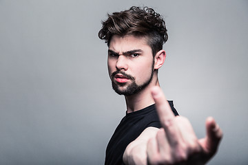 Image showing Young man in  black T-shirt showing middle finger