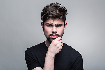 Image showing Young handsome man doubting on gray background 