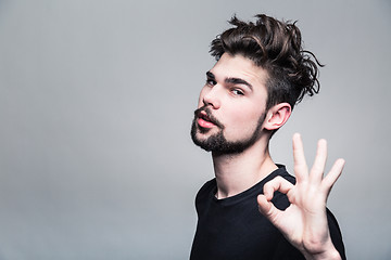 Image showing Young man in  black T-shirt shows gesture ok