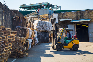 Image showing Forklift operator handling wooden pallets in warehouse