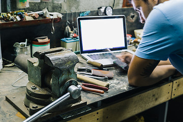 Image showing Young man at workshop using mobile phone