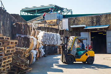 Image showing Forklift operator handling wooden pallets in warehouse