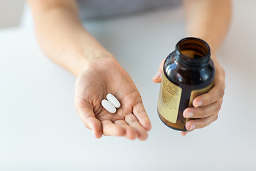 Image showing close up of hands holding medicine pills and jar