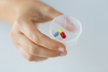 Image showing close up of female hand with pills in medicine cup