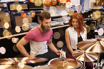 Image showing happy man and woman playing cymbals at music store