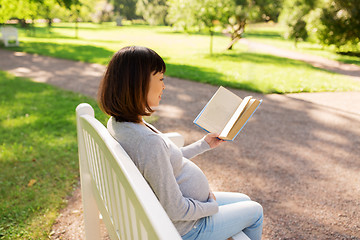 Image showing happy pregnant asian woman reading book at park