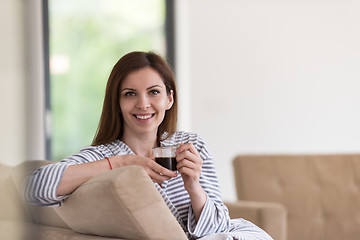 Image showing young woman in a bathrobe enjoying morning coffee