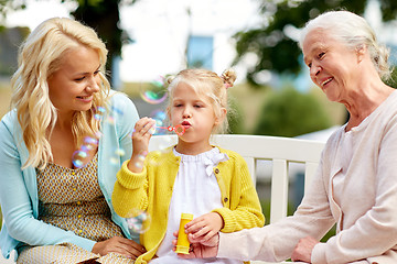 Image showing happy family blowing soap bubbles at park