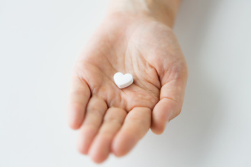 Image showing close up of hand holding medicine heart pill