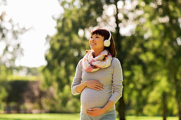 Image showing happy pregnant asian woman in headphones at park