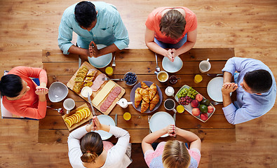 Image showing group of people at table praying before meal