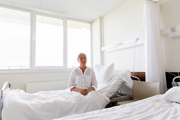 Image showing sad senior woman sitting on bed at hospital ward