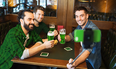 Image showing friends taking selfie with green beer at pub