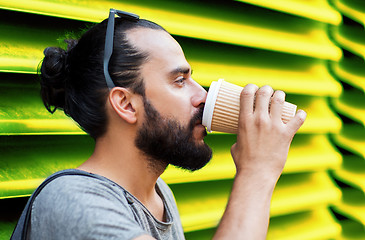 Image showing man drinking coffee from paper cup over wall