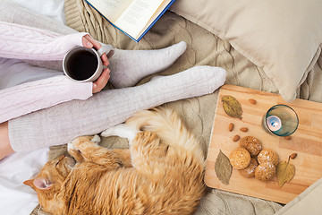 Image showing woman with coffee and red cat sleeping in bed