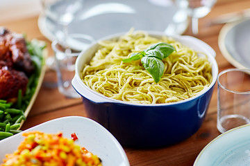 Image showing pasta with basil in bowl and other food on table