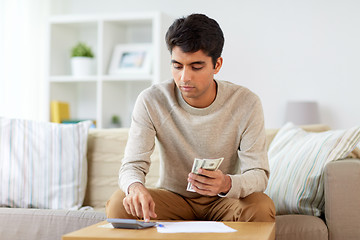 Image showing man with calculator counting money at home