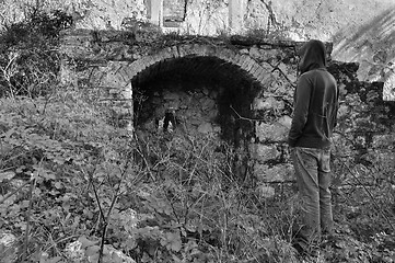 Image showing hooded man next to arched recess of rural ruin