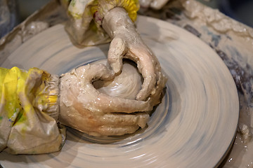 Image showing Hands of young girl in process of making clay bowl on pottery wh