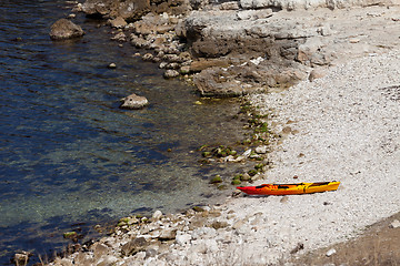 Image showing Orange kayak on pebbly beach of sea coast at sun summer day