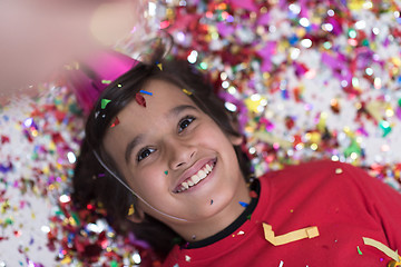 Image showing kid blowing confetti while lying on the floor