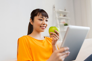 Image showing happy asian woman with tablet pc and apple at home