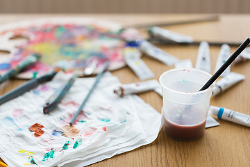 Image showing paintbrush soaking in cup of water on table