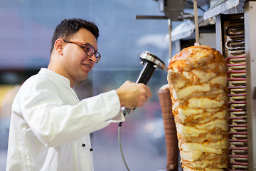 Image showing chef slicing doner meat from spit at kebab shop