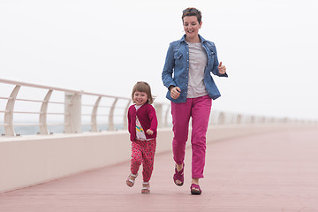 Image showing mother and cute little girl on the promenade by the sea