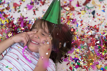 Image showing kid blowing confetti while lying on the floor