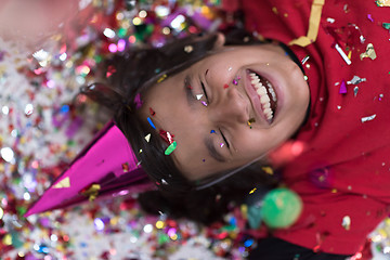 Image showing kid blowing confetti while lying on the floor