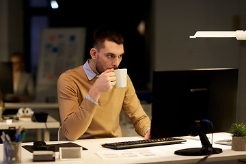 Image showing man with laptop and coffee working at night office