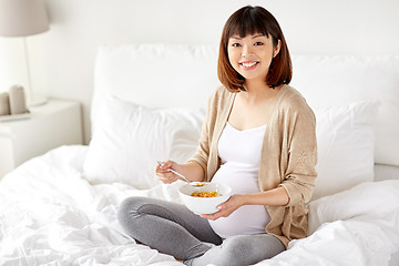 Image showing happy pregnant woman eating cereal flakes at home