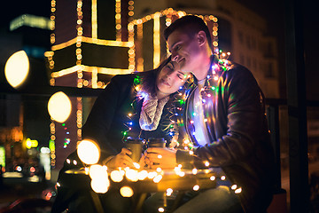 Image showing Young couple kissing and hugging outdoor in night street at christmas time