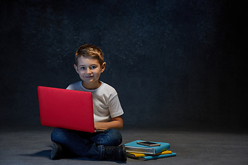 Image showing Little boy sitting with laptop in studio