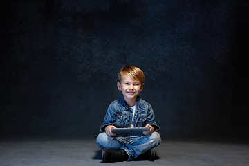 Image showing Little boy sitting with tablet in studio