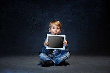 Image showing Little boy sitting with tablet in studio