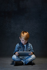 Image showing Little boy sitting with tablet in studio